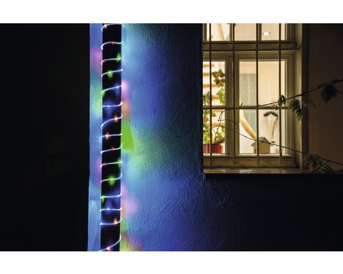 Photo extérieure d'un mur de maison avec une guirlande lumineuse LED fixée à côté d'une fenêtre.