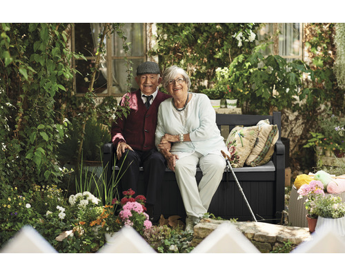 Couple âgé assis sur un banc de jardin avec rangement dans un jardin luxuriant