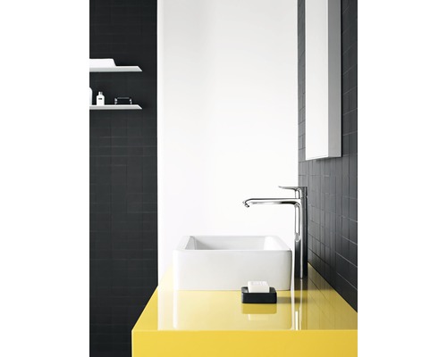 Modernes Badezimmer mit Waschbecken, Armatur und gelber Ablagefläche vor schwarzem Fliesenspiegel