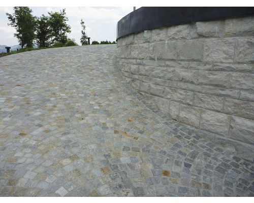 Surface pavée avec mur en pierre naturelle à l''extérieur.