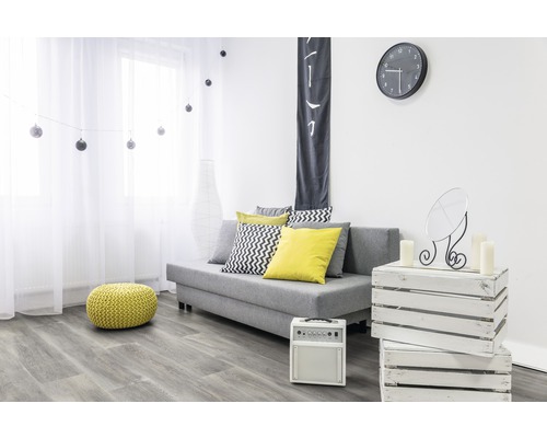 Wohnzimmer mit Sofa, Kissen, Pouf, Uhr und Dekorationen