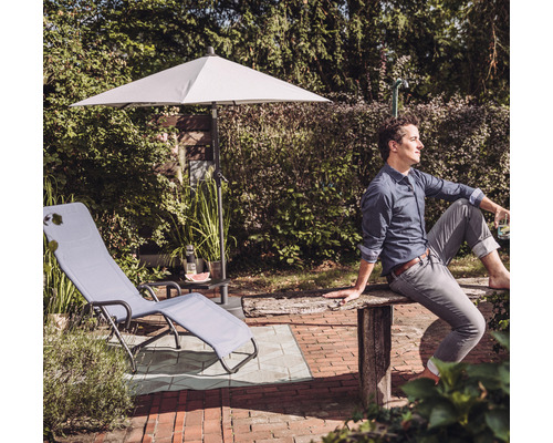 Scène de jardin avec chaise longue, parasol et homme dans le jardin