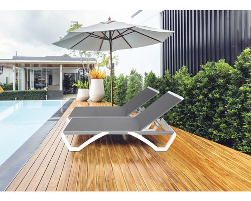 Zwei graue Liegestühle aus Kunststoff mit Sonnenschirm neben einem Schwimmbad.