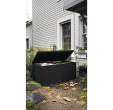 Coffre de jardin noir ouvert sur une pelouse devant une maison