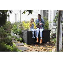 Une femme et un enfant sont assis sur un coffre de jardin dans le jardin.