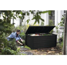 Scène de jardin avec une femme agenouillée à côté d''un coffre de jardin noir ouvert