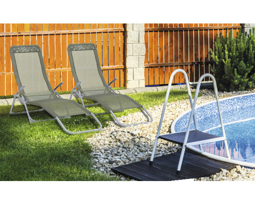 Zwei Liegestühle aus Metall und Textil neben einem Schwimmbecken mit einer Leiter.