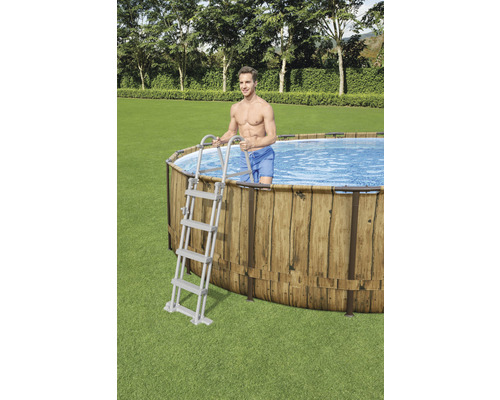 Piscine ovale avec revêtement en bois et échelle dans le jardin.