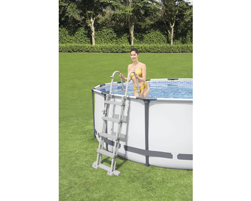 Piscine hors-sol avec échelle et femme dans le jardin.