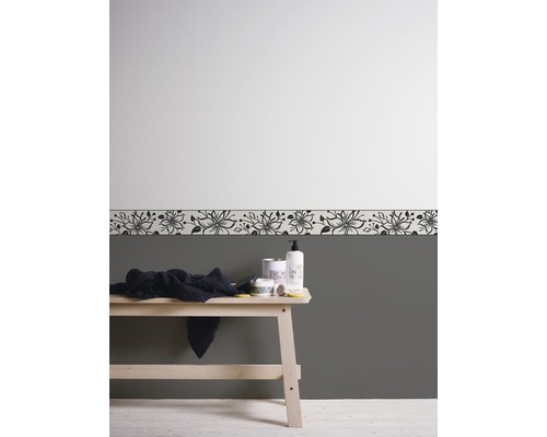 Aménagement de salle de bains avec bordure florale, serviette et produits de soins sur un banc en bois.