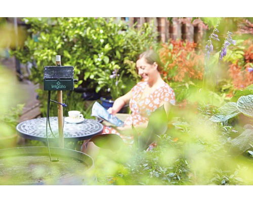 Arrosage automatique dans le jardin avec une femme lisant en arrière-plan