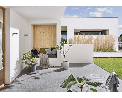 Terrasse lumineuse avec coin salon, mur en bois, plantes et vue sur le jardin