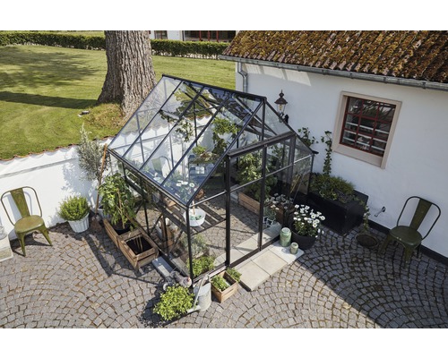 Gewächshaus mit Pflanzen und Gartenmöbeln im Aussenbereich