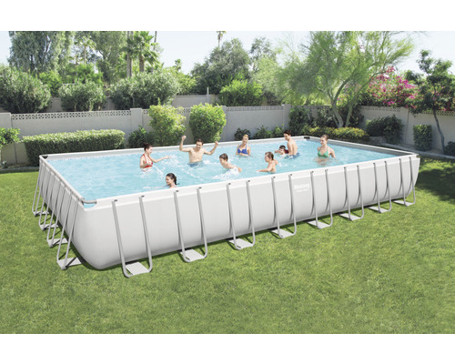Piscine rectangulaire avec cadre en acier dans le jardin avec des personnes qui jouent.