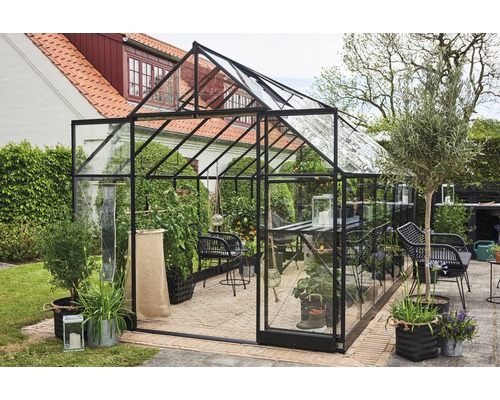 Gewächshaus mit Pflanzen und Gartenmöbeln im Aussenbereich.