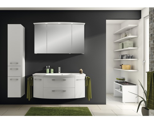 Badezimmer mit weißem Waschtisch, Spiegelschrank, Hochschrank und Regalen für Badutensilien.