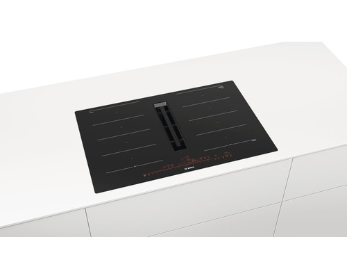 Plaque à induction noire avec hotte aspirante de Bosch sur un plan de travail blanc.