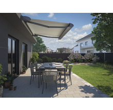 Terrasse mit Markise, Gartentisch und Stühlen vor einem Haus.