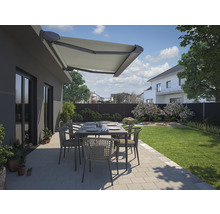 Terrasse mit Markise, Tisch und Stühlen vor einem Haus mit Garten