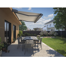 Terrasse mit Markise, Tisch und Stühlen in einem Garten.