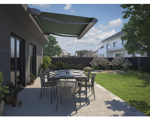 Terrasse mit Markise, Gartentisch und Stühlen vor einem Haus.