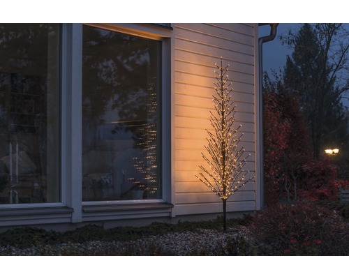 Beleuchteter Deko-Baum vor einem Haus im Aussenbereich.