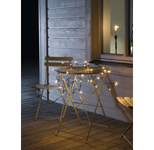 Scène de jardin avec guirlande lumineuse sur table et chaises sur une terrasse