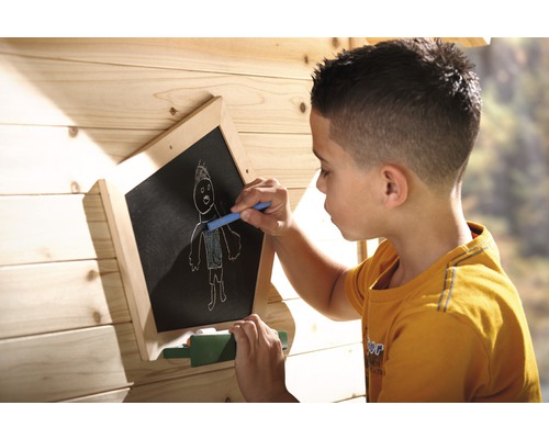 Garçon dessine à la craie sur un tableau noir dans une cabane de jeu