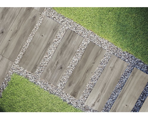 Gartenszene mit Gehwegplatten in Holzoptik, eingefasst von Kies und Rasen