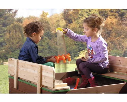 Deux enfants jouent dans un bac à sable avec des jouets de sable.