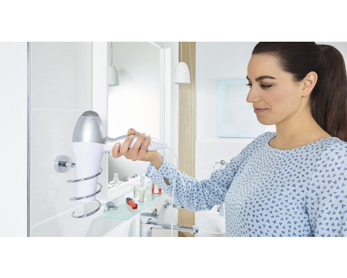 Femme prend un sèche-cheveux sur son support dans la salle de bains