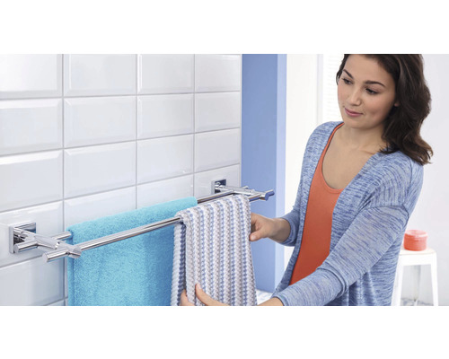 Une femme accroche des serviettes à un porte-serviettes dans la salle de bain.