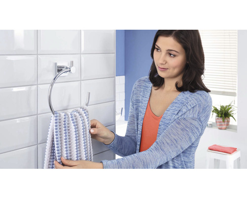 Frau hängt Handtuch auf Handtuchhalter im Badezimmer