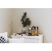 Dekorative Popcornfabrik als leuchtendes Deko-Element neben Geschenk und Vase mit Tannenzweigen auf einer Kommode