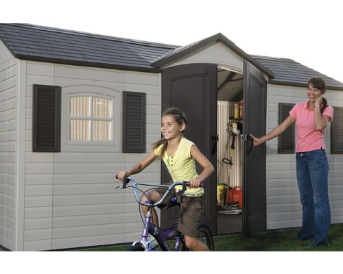 Abri de jardin avec porte ouverte, enfant jouant sur un vélo et femme