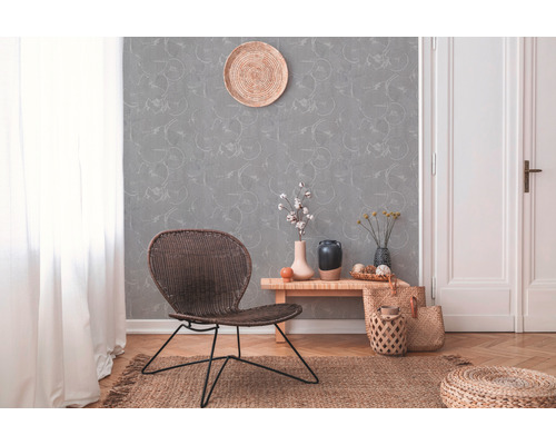 Dekorativer Wohnraum mit Rattansessel, gemusterter Tapete und Holzboden