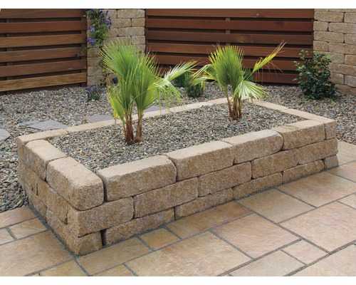 Hochbeet aus Steinblöcken mit Pflanzen und Kies im Garten