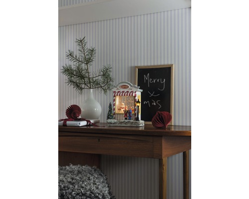 Dekoratives Weihnachtsstilleben mit beleuchteter Schneekugel auf einem Holztisch