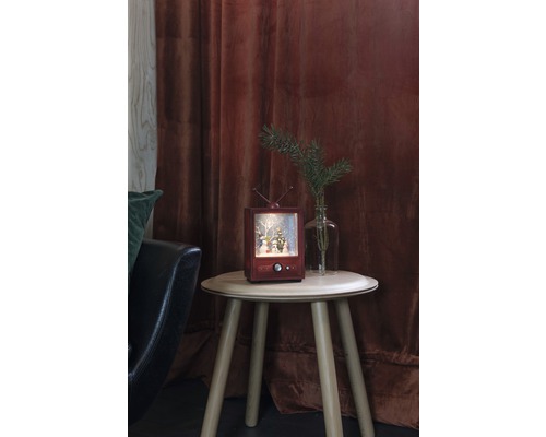 Boule à neige décorative en forme de téléviseur sur une petite table avec décoration