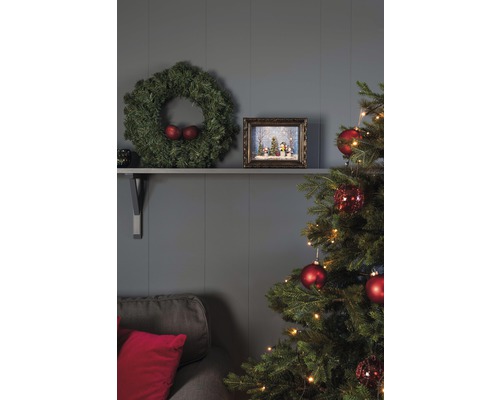 Salon décoré pour les fêtes avec sapin de Noël, couronne et décorations sur une étagère