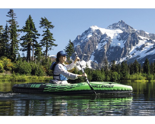 Une femme fait du kayak Intex Challenger sur un lac avec une montagne en arrière-plan.