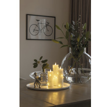 Arrangement décoratif avec bougies LED, vases et une sculpture sur une table