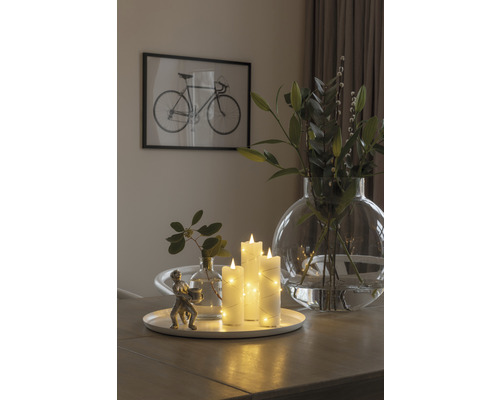 Arrangement décoratif avec bougies LED, vases et une sculpture sur une table