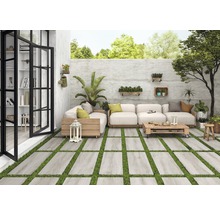 Helle Terrasse mit Steinplatten und Rasen, Sitzgruppe mit Holzelementen und dekorativen Pflanzen