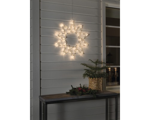 LED Acryl Stern Konstsmide 60 LEDs Lichterfarbe warmweiss Dekorativer beleuchteter Stern hängt an einer Hauswand, Tisch mit Weihnachtsdekoration