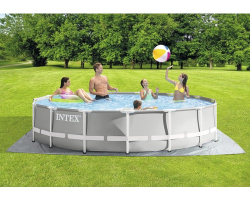 Famille avec piscine gonflable dans le jardin avec tapis de sol et ballon.