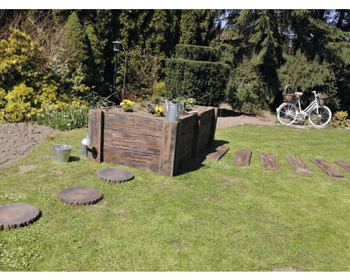 Gartenszene mit Hochbeet, Trittplatten und dekorativem Fahrrad