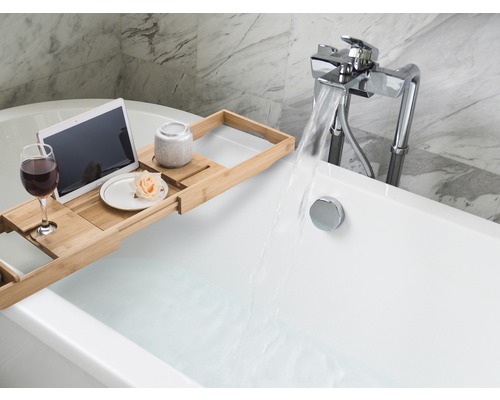 Szene eines gefüllten Badezubers mit ausziehbarem Badewannenregal, Tablet, Glas Wein, Keramikgefäß und Blume