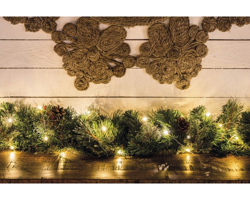 Arrangement décoratif avec couronne de jute, vert sapin, guirlande lumineuse et pommes de pin