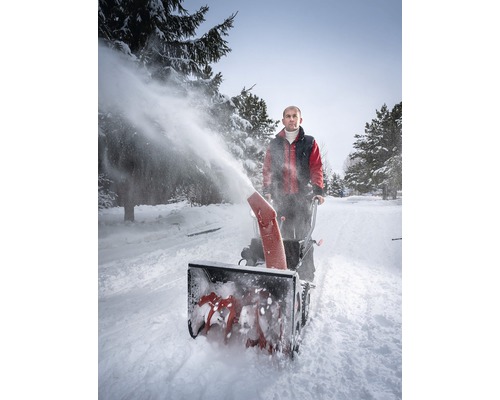 Eine Person benutzt eine Schneefräse, um einen Weg von Schnee zu befreien.